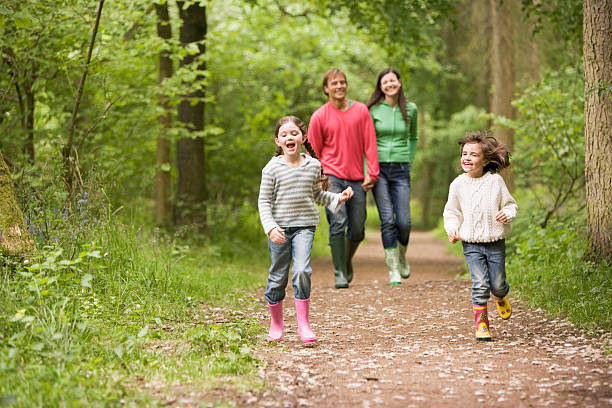 famille heureuse marchant sur un sentier dans les bois - marcher foret photos et images de collection