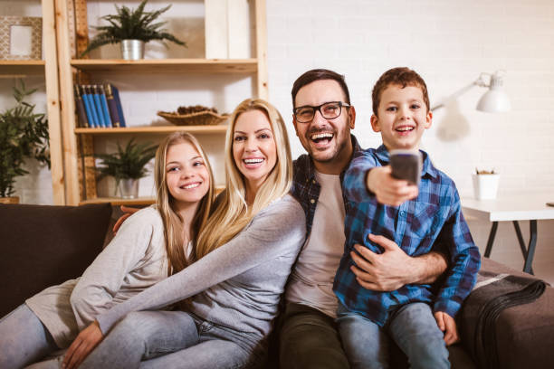 Happy family watching TV together at home and having fun together. stock photo