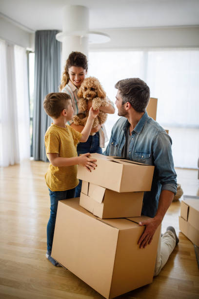 Happy family with children moving with boxes in a new apartment house. stock photo