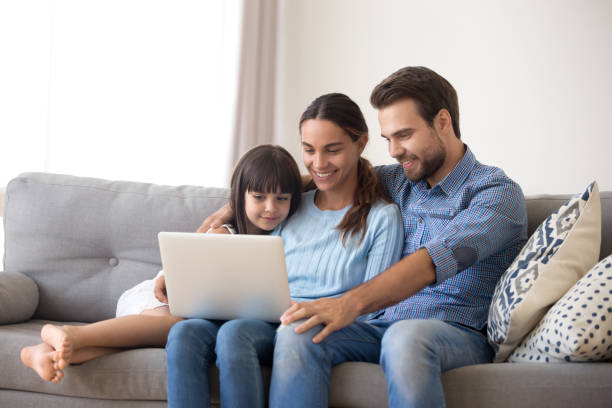 szczęśliwa rodzina z dzieckiem córka cieszyć się za pomocą laptopa w domu - video call zdjęcia i obrazy z banku zdjęć
