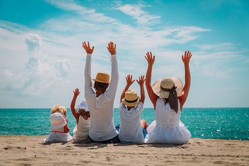 happy family with kids hands up on beach, vacation concept