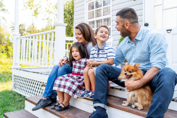 Happy family with two kids sitting in front of american porch stock photo