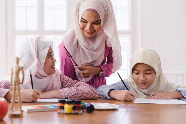 Happy family.Muslim woman teaching her kids painting and drawing at home. Happy family.Muslim woman teaching her kids painting and drawing at home. indonesian girl stock pictures, royalty-free photos & images