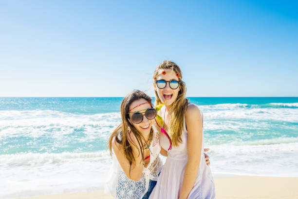 Happy fashionable young friends playing on the beach stock photo