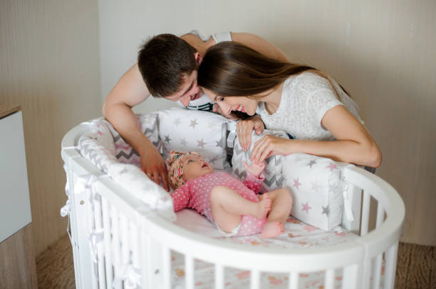 gelukkig vader en moeder lulling schattig klein pasgeboren babymeisje in bed - wiegman stockfoto's en -beelden