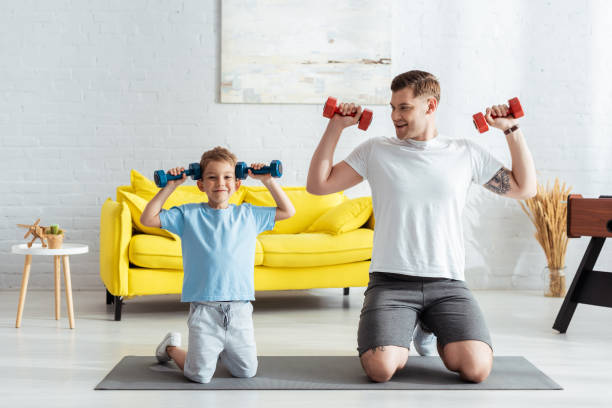 pai e filho feliz se exercitando com halteres enquanto de pé de joelhos no tapete fitness - son dad workout - fotografias e filmes do acervo
