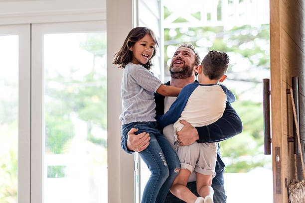 Happy father greeting his children Happy father arriving home and greeting his children with a hug and big smile. worker returning home stock pictures, royalty-free photos & images