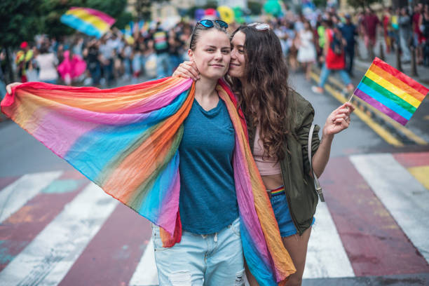 Happy female couple hugging and kissing at the gay pride parade stock photo