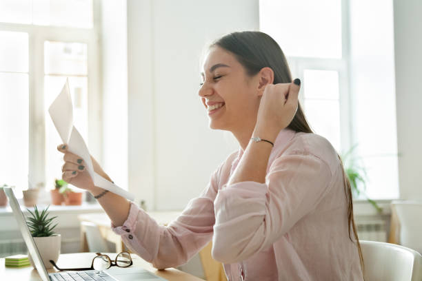 Happy female employee excited reading promotion letter Happy female worker excited getting business letter with promotion news, satisfied woman celebrating corporate success reading report with great result or personal achievement. Rewarding concept read notes stock pictures, royalty-free photos & images