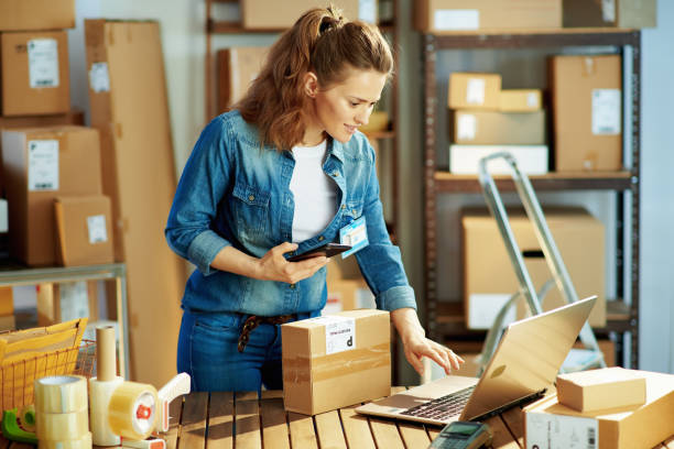 happy female in jeans using phone applications in warehouse stock photo