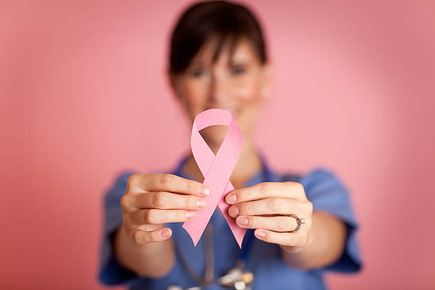Happy Female Nurse Holding Pink Breast Cancer Awareness Ribbon stock photo