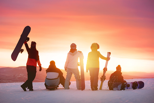 Happy friends at ski resort against sunset