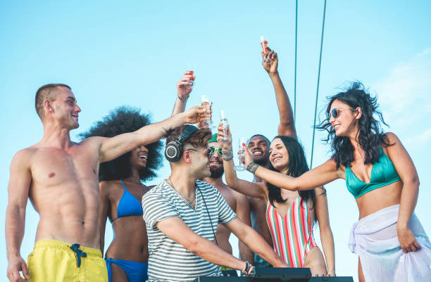 夏のボートパーティーでシャンパンを飲む幸せな友人 - 若いミレニアル世代の人々は、djミキシング音楽と一緒に飲んで楽しんでいる - 若者のライフスタイルと休暇の概念 - センターの男に� - なるほど ストックフォトと画像