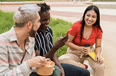 istock Happy friends having fun eating take away food outdoor in the city - Focus on asian girl face 1342449803