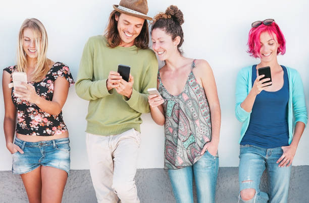 Happy friends watching on their smart mobile phones outdoor - Young generation having fun with new technology and social network - Concept of millennials people, tech and youth addiction lifestyle  auto post production filter stock pictures, royalty-free photos & images