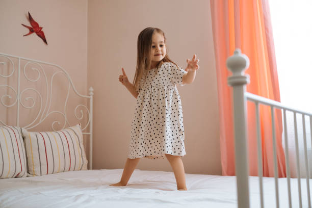 niña feliz y divertida saltando en la cama sola sintiendo jo - mattresses for children  fotografías e imágenes de stock