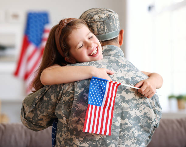 Happy girl daughter with american flag hugging father came back from US army stock photo