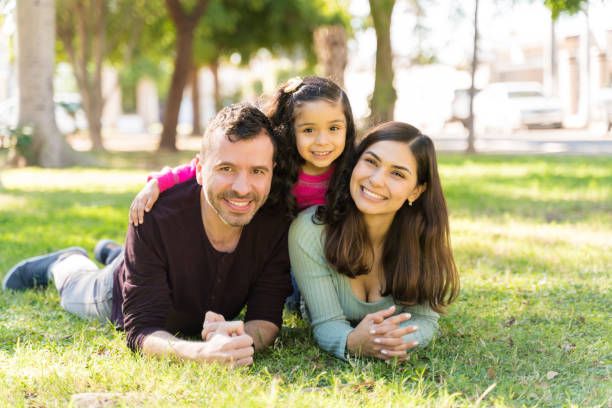 Happy Girl Enjoying Weekend With Parents Smiling Family Lying On Grass At Park During Sunny Day mexico photos stock pictures, royalty-free photos & images