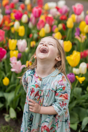 Happy girl laughs in a park with the tulips