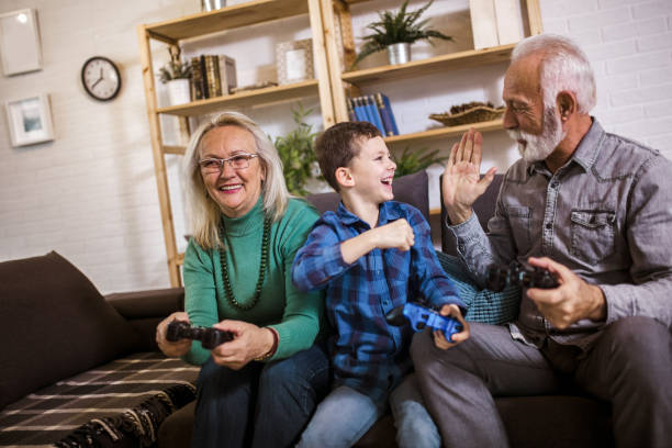 Happy grandparents playing video games with their grandson stock photo