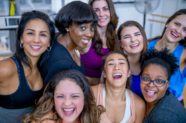 Happy Group At Gym A multi-ethnic group of adult women are laughing while posing for a group photo. They are in a health center, and they are wearing sports clothing. 40 49 years photos stock pictures, royalty-free photos & images