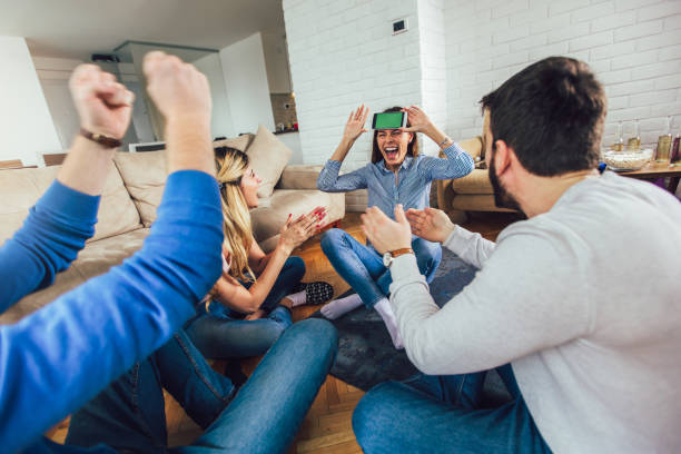 Happy group of friends playing charades at home Happy group of friends playing charades at home charades stock pictures, royalty-free photos & images