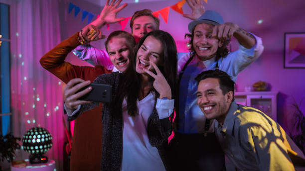 happy group of young people taking collective selfie at the wild house party. neon lights, disco ball and funny costumes. - balo~es festa imagens e fotografias de stock
