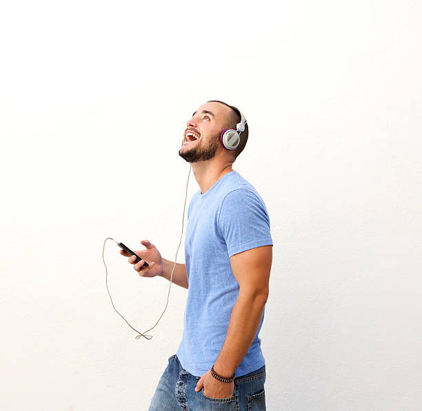 Happy guy walking with cell phone and headphones stock photo