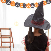 楽しいハロウィンをお過ごし下さい。魔女の衣装で小さな美しい女の子はカボチャとインテリアで家を祝う