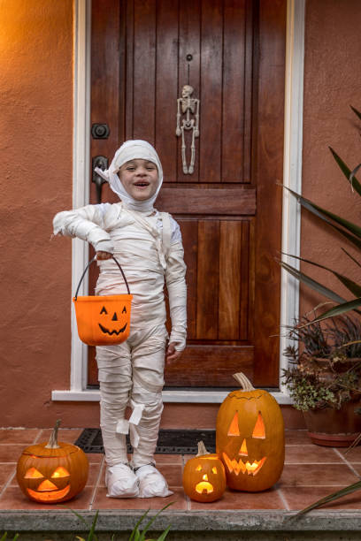 Happy Halloween-Portrait of a Mummy Happy 5 year old wearing a handmade mummy costume, trick or treating in a neighborhood stage costume stock pictures, royalty-free photos & images