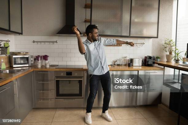 Happy handsome young African American man dancing in kitchen.