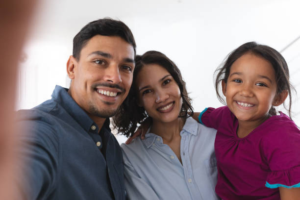 Happy hispanic couple and daughter taking selfie smiling to camera stock photo