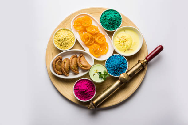 Happy Holy concept  showing Indian assorted sweets like jalebi, gujiya, than, ras malai with holi colours and pichkari, isolated over white background Happy Holy concept  showing Indian assorted sweets like jalebi, gujiya, than, ras malai with holi colours and pichkari, isolated over white background holi photos stock pictures, royalty-free photos & images