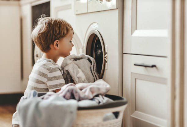 happy  householder child boy in laundry   with washing machine happy little funny householder child boy in laundry   with washing machine washing stock pictures, royalty-free photos & images