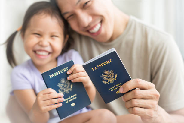 Happy immigrant family becoming new American citizens, holding US passports. Asian dad and daughter holding amercian passports with pride. Immigration citizenship immigrant stock pictures, royalty-free photos & images