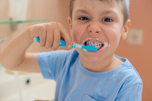 Happy kid or child brushing teeth in bathroom. stock photo