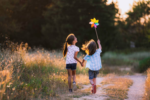 happy kids having fun with pinwheel in the nature. running kids - kind stockfoto's en -beelden