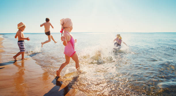 Happy kids on vacations at seaside running in the water Boys and girls playing on the beach on summer holidays. Children in nature with beautiful sea, sand and blue sky. Happy kids on vacations at seaside running in the water baltic countries stock pictures, royalty-free photos & images