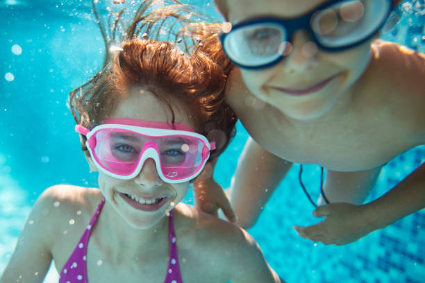 Happy kids playing underwater Brother and sister are having fun playing underwater in the resort pool.  Kids are aged 10 and 6.
 swimming goggles stock pictures, royalty-free photos & images