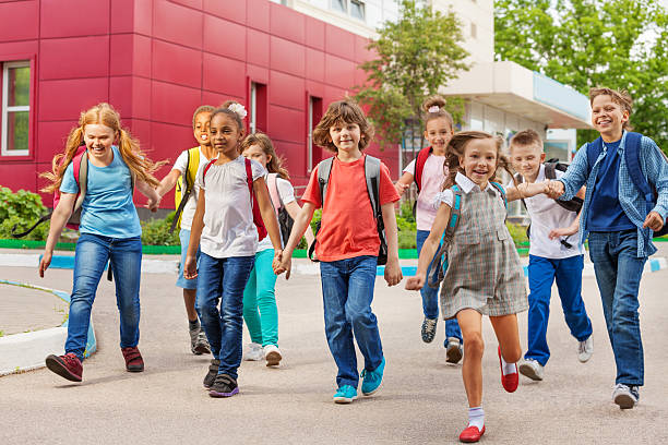 happy kids with rucksacks walking holding hands - hogeschool rood samen stockfoto's en -beelden