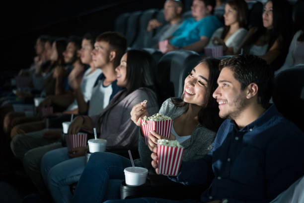 Happy Latin American couple at the movies Portrait of a happy Latin American couple at the movies eating popcorn and watching a film movie stock pictures, royalty-free photos & images
