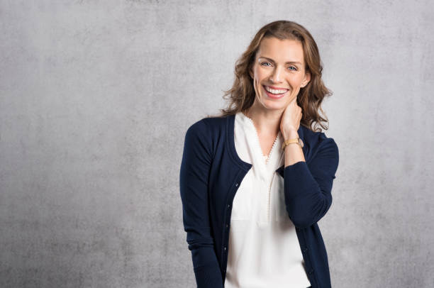 Happy laughing woman Cheerful mid adult woman laughing and looking at camera. Portrait of smiling businesswoman enjoying standing against grey wall. Happy mature woman looking at camera with toothy smile, copyspace. mid adult women stock pictures, royalty-free photos & images