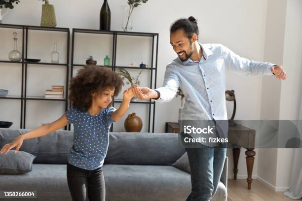 Happy little African American kid dancing with father.