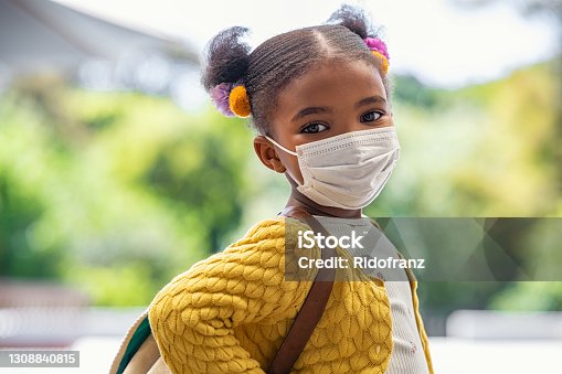 istock Happy little black girl with face mask ready to go to elementary school 1308840815
