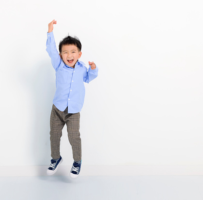 Happy little boy jumping on white background
