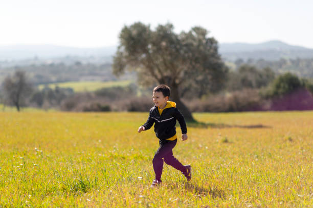 Happy little boy running on meadow stock photo
