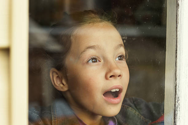 happy little girl looking through an old window - omg girl bildbanksfoton och bilder