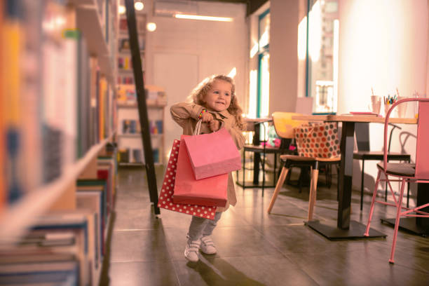 happy little girl running with shopping bags - foster home bag imagens e fotografias de stock