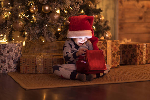 happy little smiling boy with christmas gift. - christmas magic imagens e fotografias de stock
