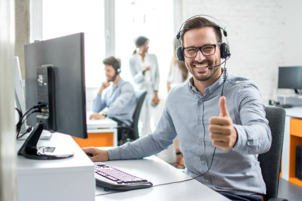 Happy male customer service operator showing thumb up in office. stock photo